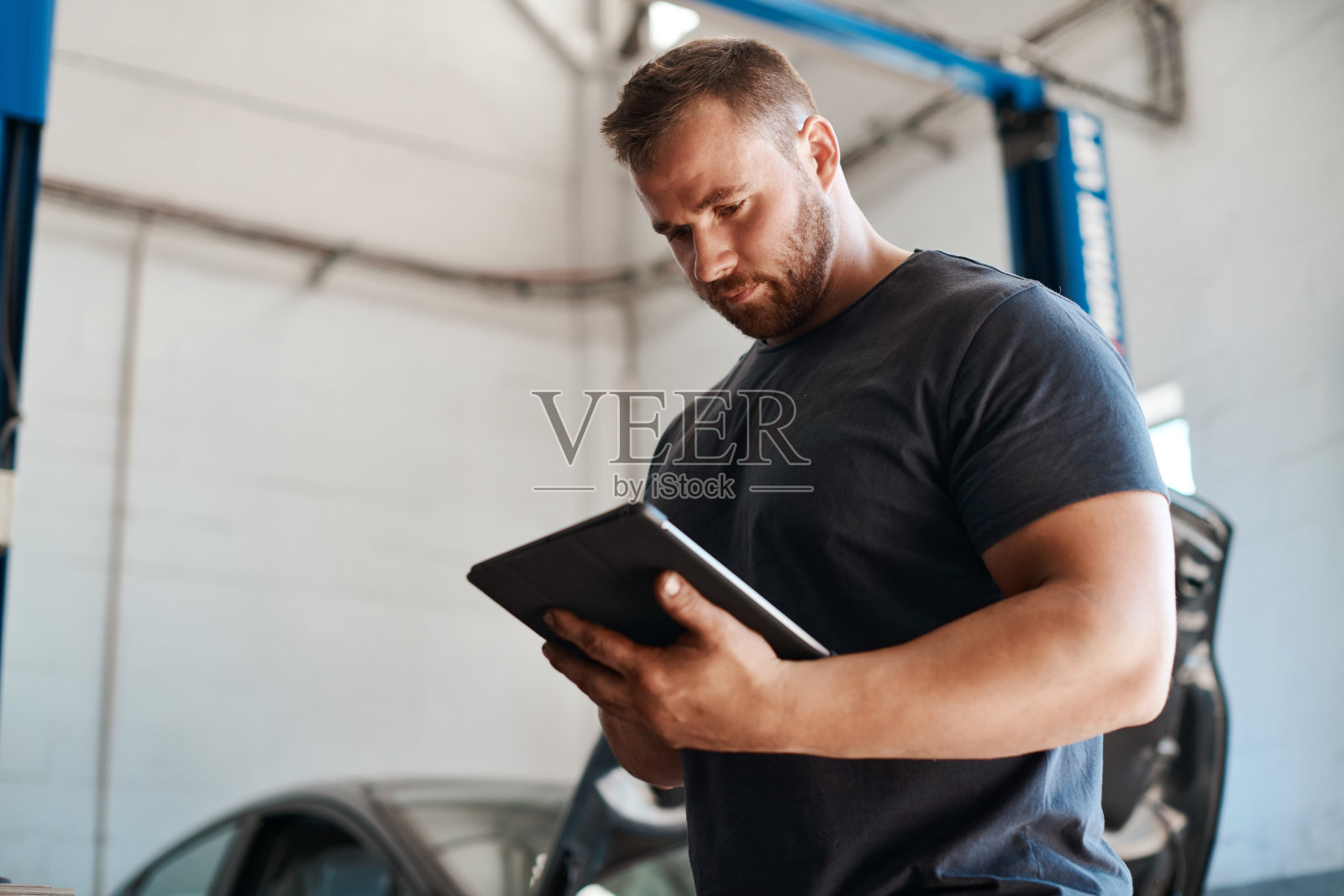 图为一名修车工在汽车修理厂工作时使用数码平板电脑照片摄影图片