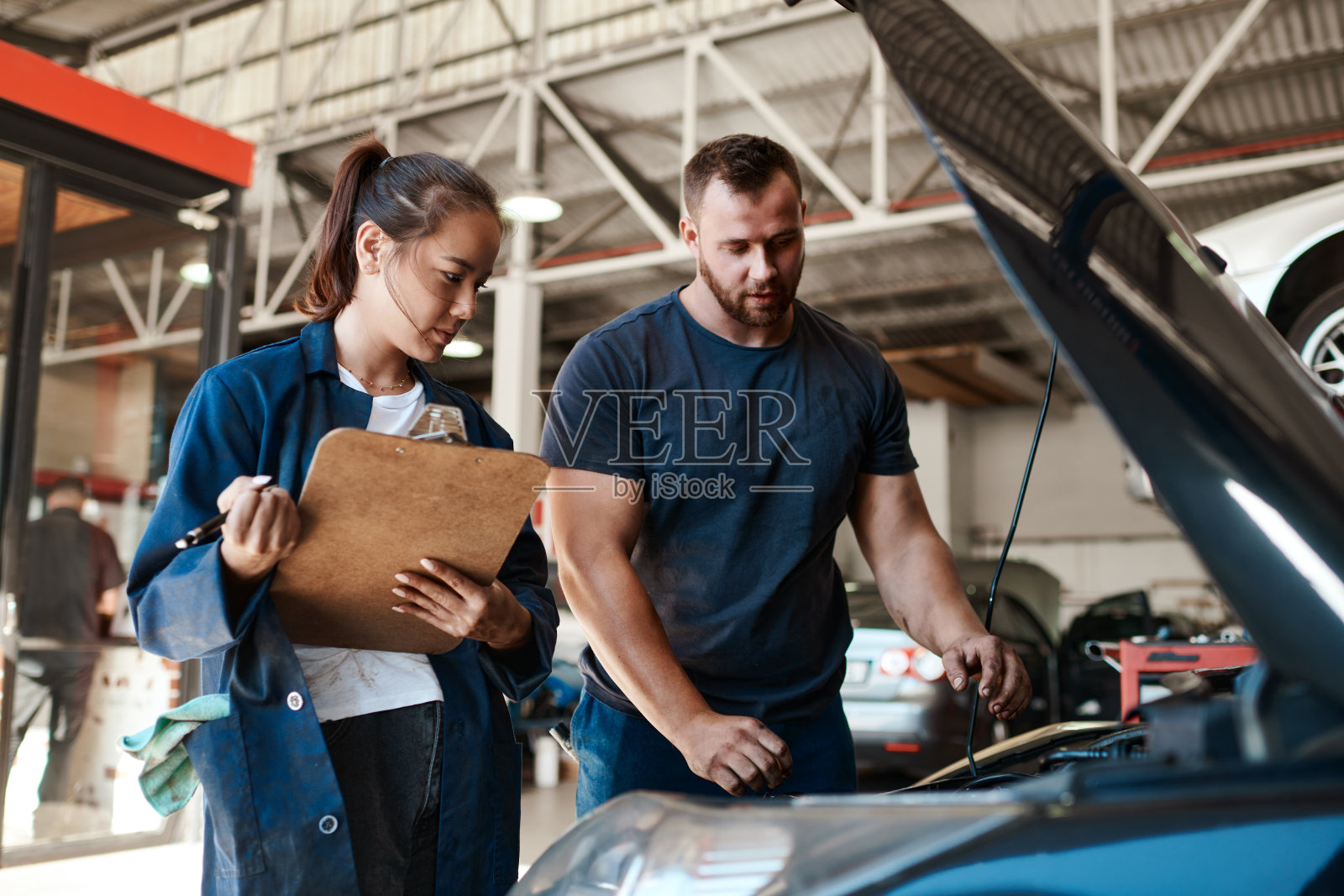 两个机械师在汽车修理厂一起修理一辆汽车照片摄影图片