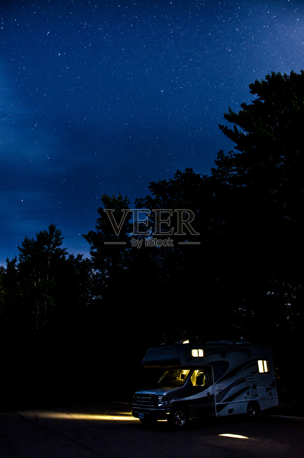 在繁星点点的夏夜，停在停车场的房车照片摄影图片