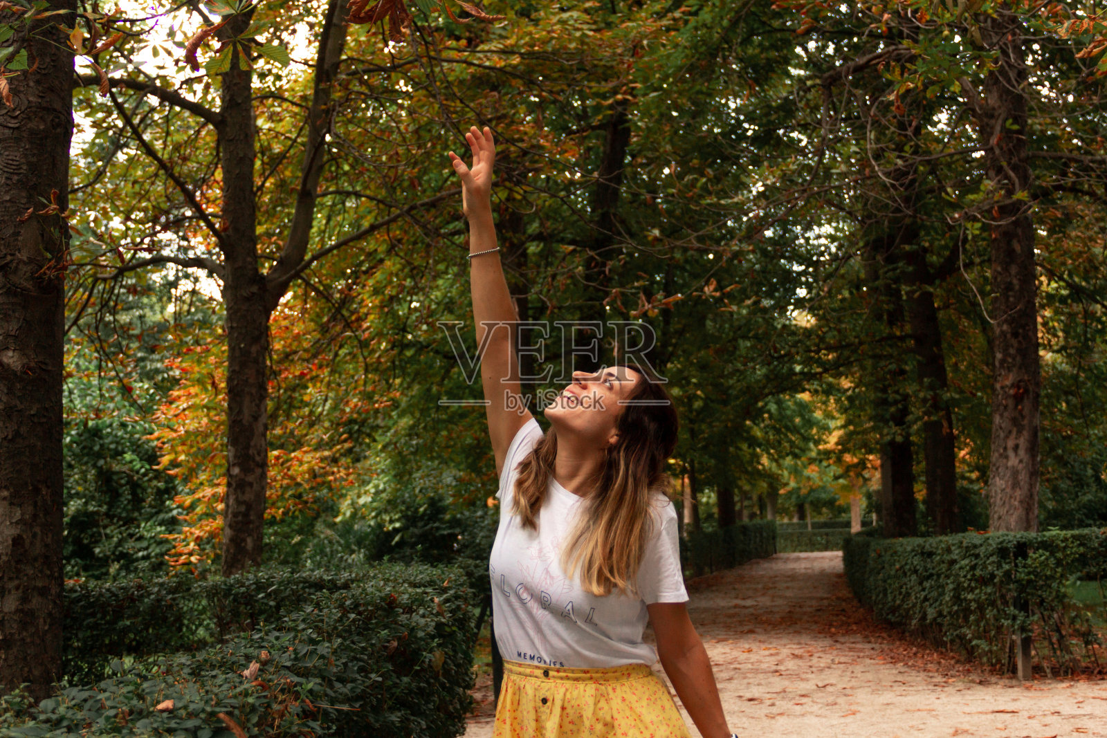 年轻女子在秋天的公园里微笑着玩树叶。有选择性的重点。照片摄影图片