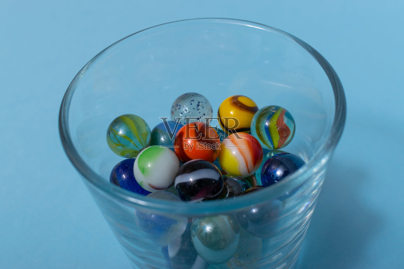 彩色玻璃弹珠孤立在蓝色背景上，靠近玩具。照片摄影图片