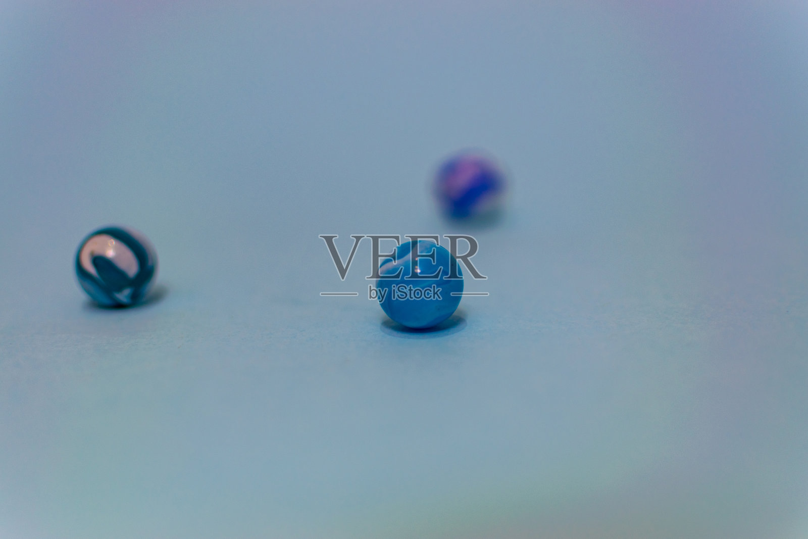 彩色玻璃弹珠孤立在蓝色背景上，靠近玩具。照片摄影图片