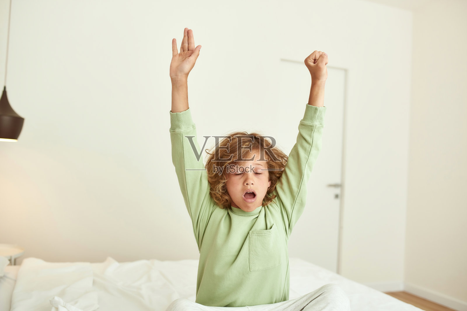 少年伸伸懒腰，早上在床上醒来照片摄影图片