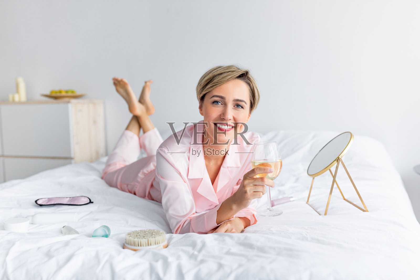 一个快乐的女人躺在床上喝酒照片摄影图片