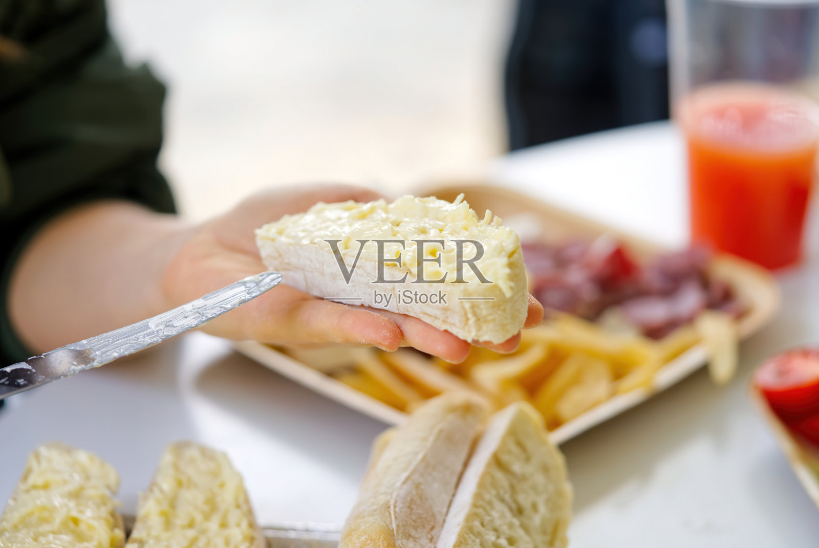 一个女人用手把奶酪涂在面包上，沙拉上放了大蒜。为烧烤聚会准备点心的过程照片摄影图片