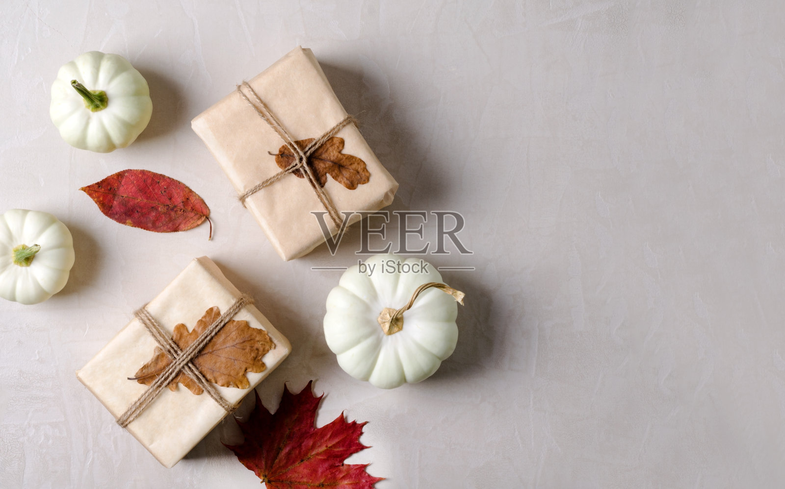 米色背景的牛皮纸和南瓜礼物。秋天的温暖的背景照片摄影图片
