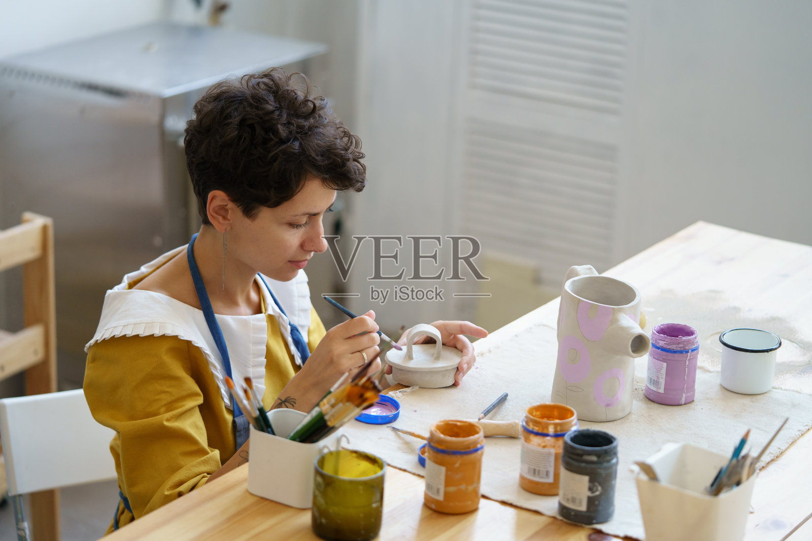 艺术职业:年轻女子在工作之余学习陶艺，开陶艺工作室做小生意照片摄影图片