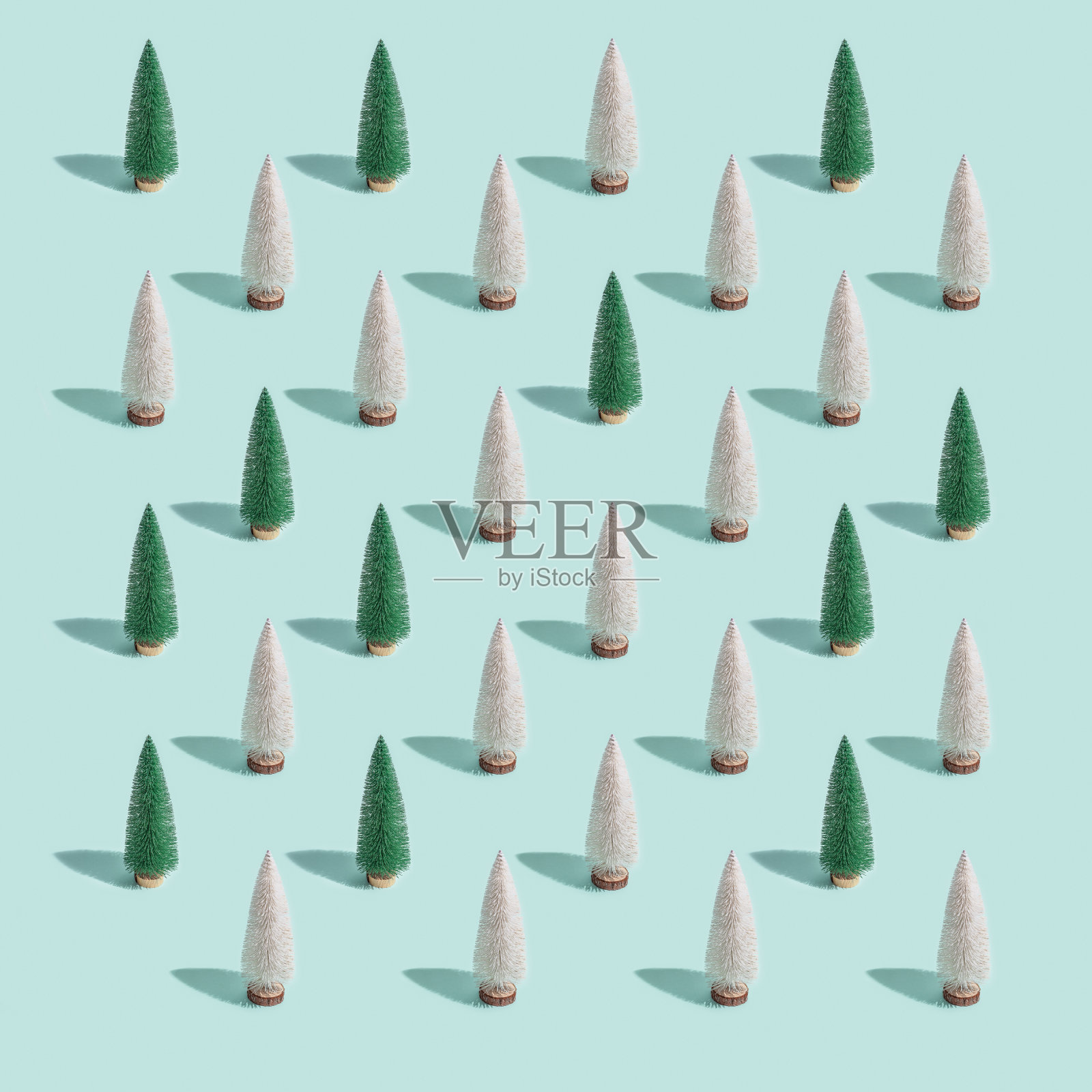 闪亮的圣诞树图案，明亮的白色和绿色冷杉在柔和的蓝色背景。冬天的节日快乐。新年最低卡。插画图片素材