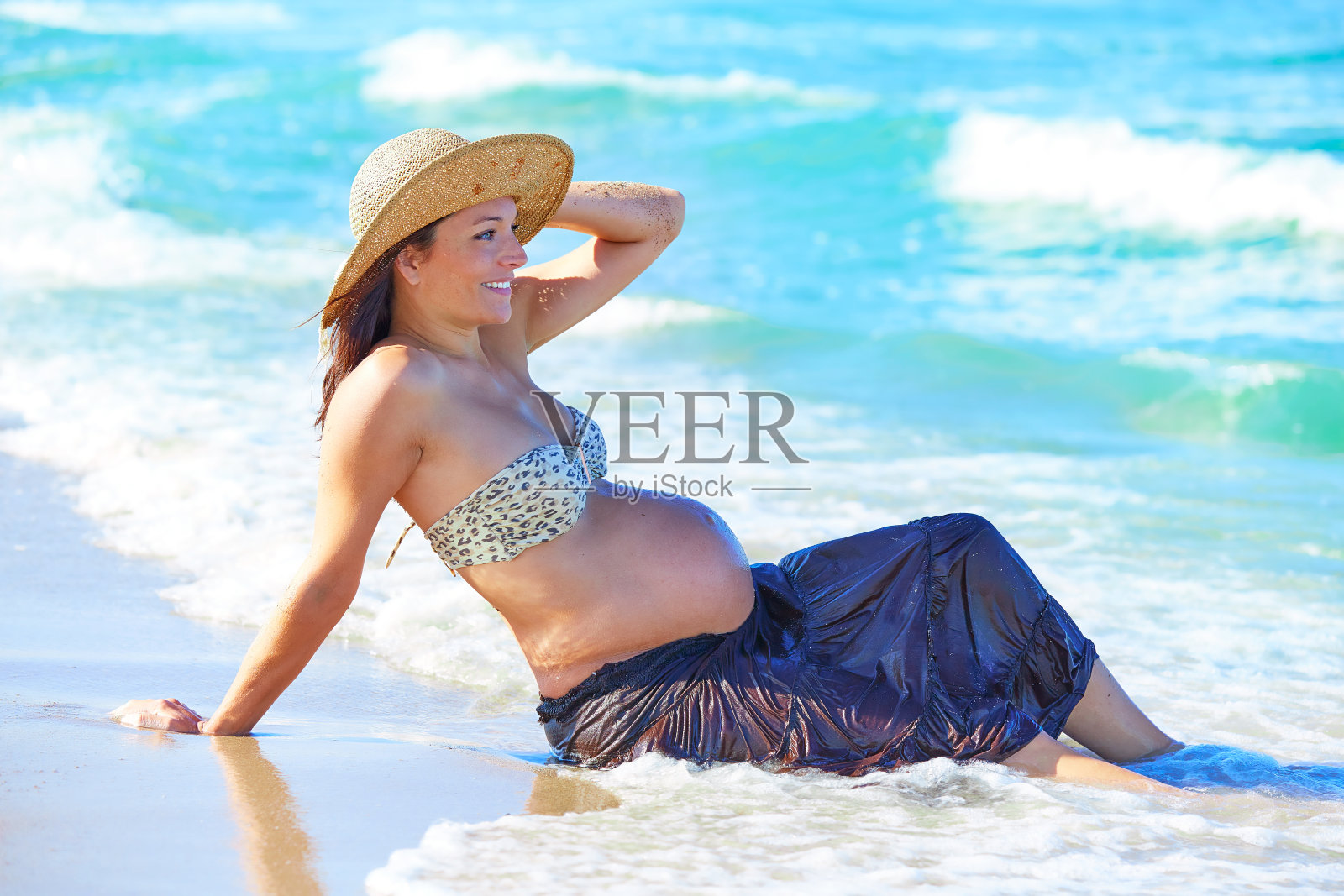 孕妇在沙滩上与海浪嬉戏照片摄影图片