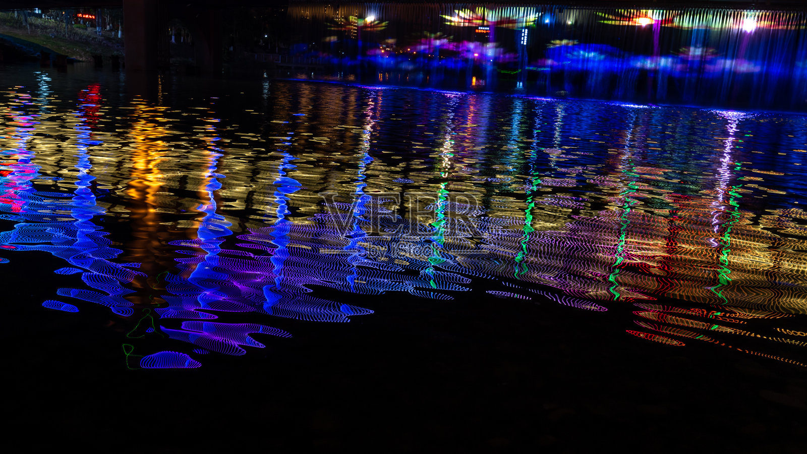 晚上，小溪反射着桥上五颜六色的灯光照片摄影图片