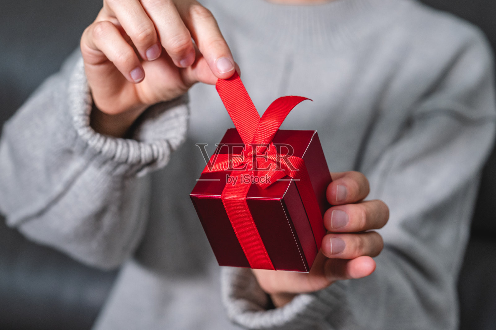 红色礼品盒，手里拿着红色蝴蝶结。圣诞节，新年，生日和情人节礼物照片摄影图片