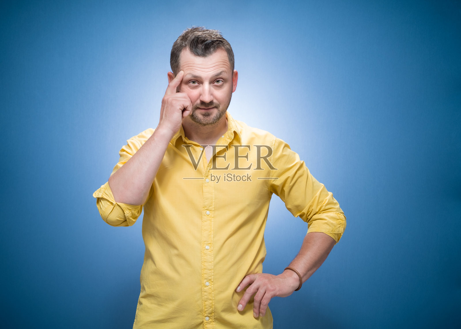 狡猾的年轻人问道。在蓝色背景上复制空间，穿着黄色衬衫。半长的家伙在问概念照片摄影图片