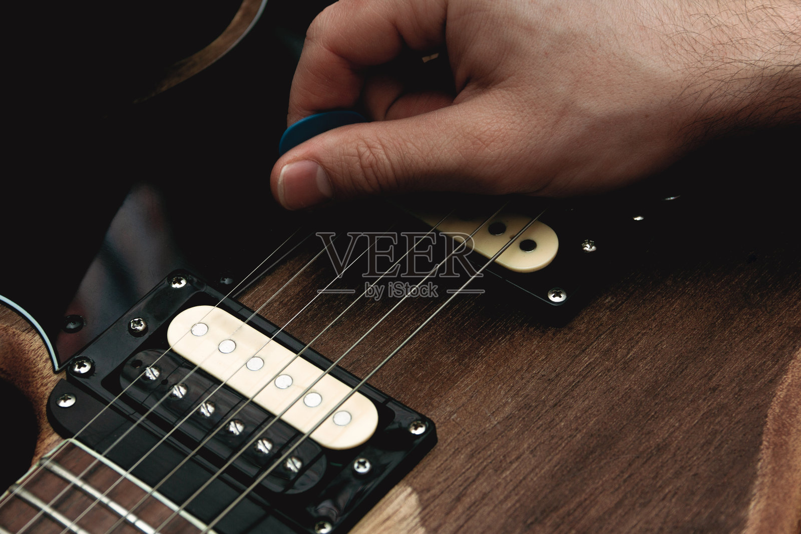 用拨子拨电吉他琴弦的人。有选择性的重点。副本的空间。照片摄影图片