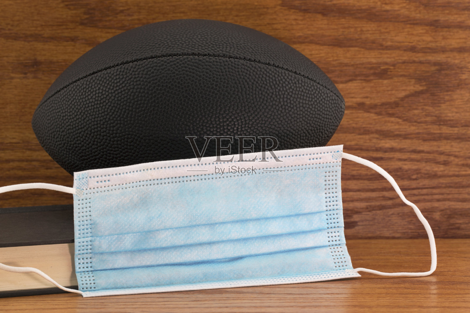 黑色足球放置书籍和医用防护口罩照片摄影图片