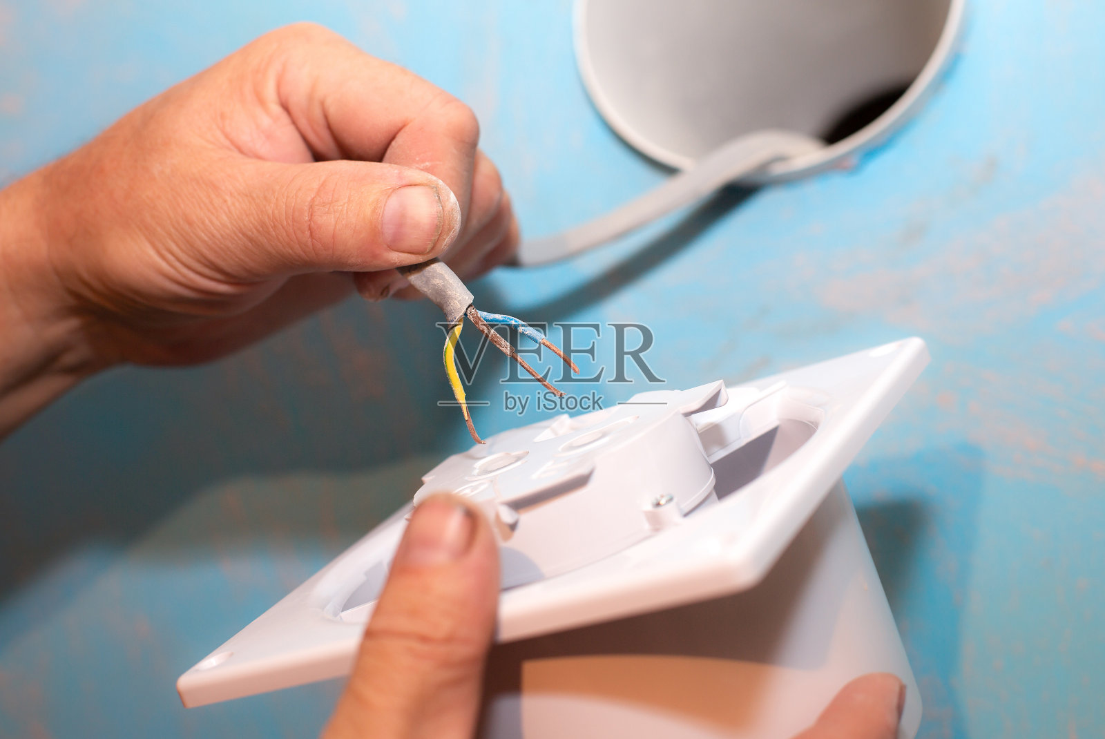 一名男子正在安装浴室的通风口。恢复的过程。电线在手中。维修保养工程装修单位。照片摄影图片