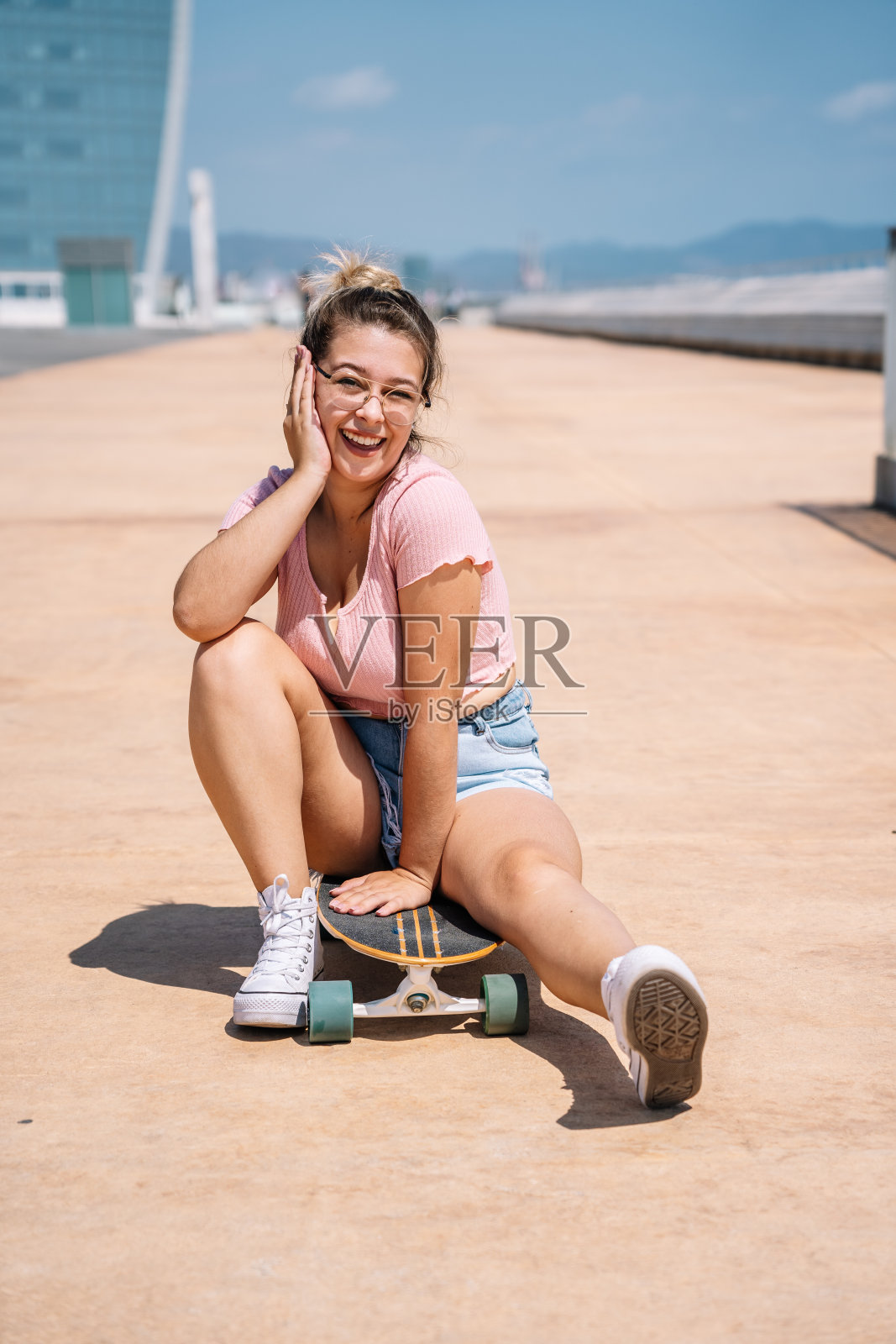 描绘年轻的金发女人戴着眼镜玩滑板照片摄影图片