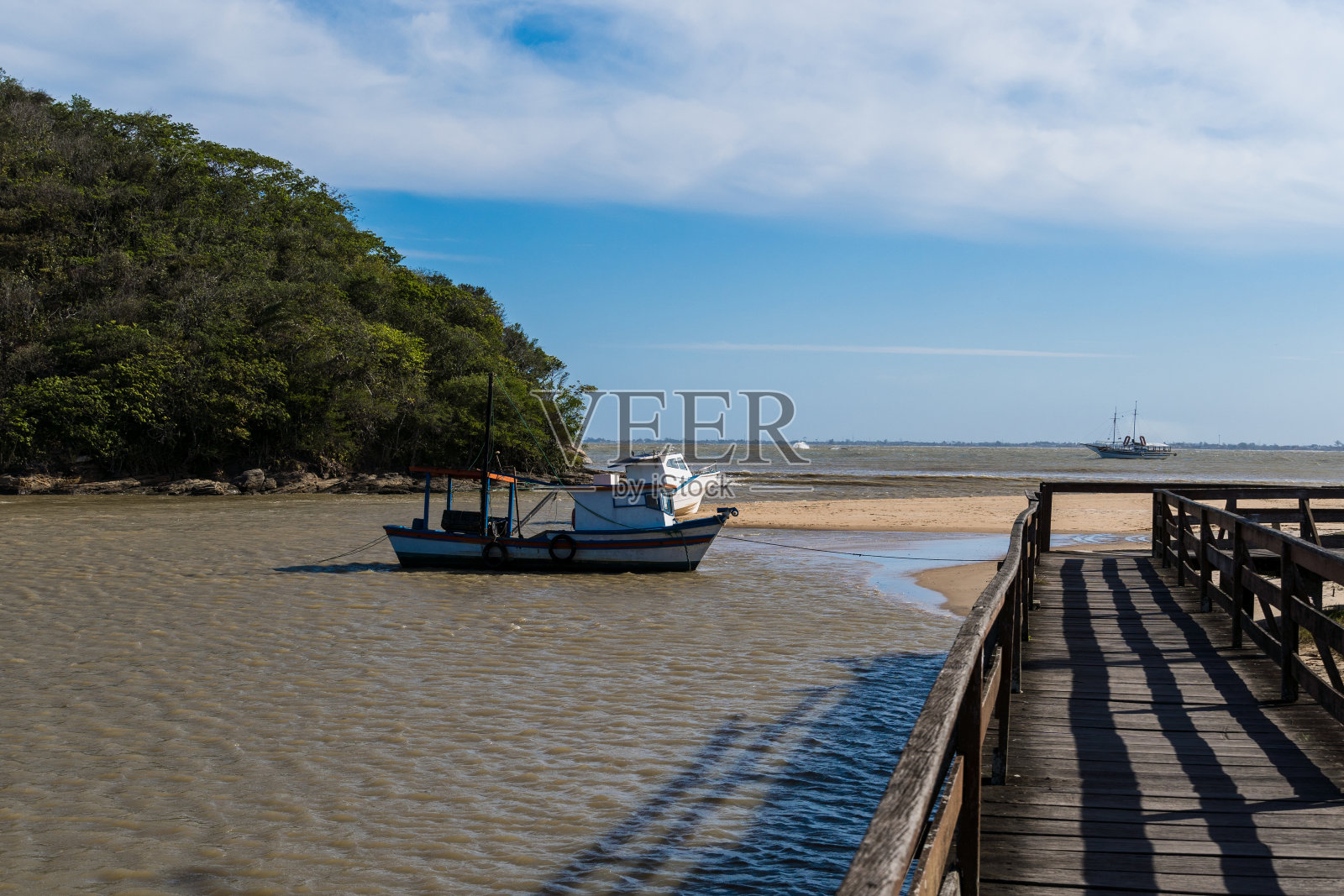奥斯特拉斯海滩与里约热内卢河交汇处的景色。晴天，蓝天。黄色的沙子和一些岩石。木桥要过。在码头上捕鱼照片摄影图片