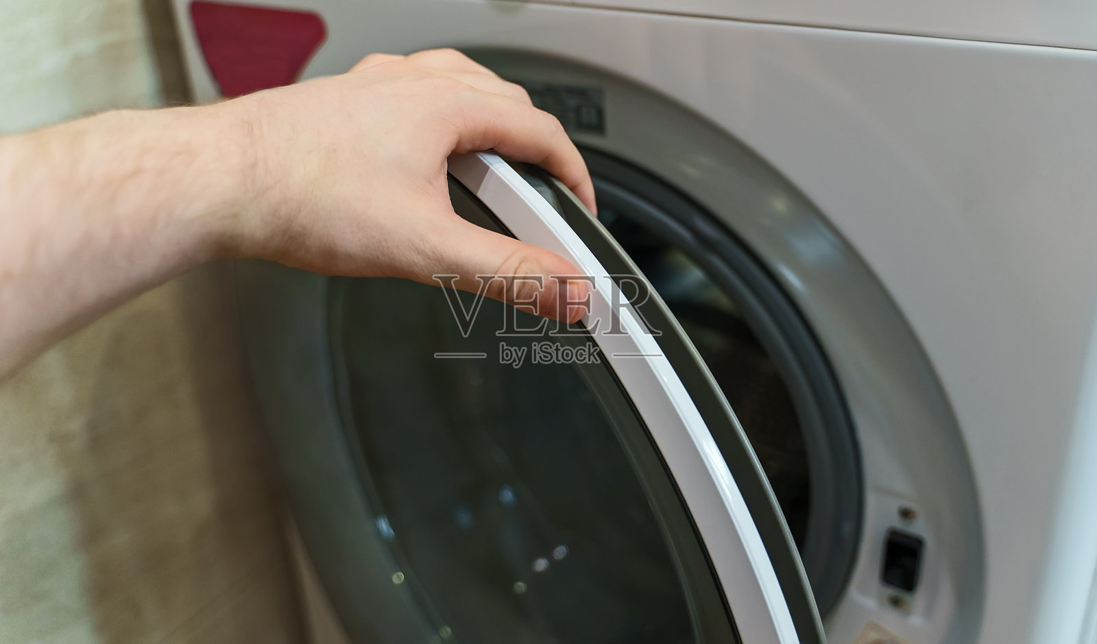 男子打开洗衣机门。照片摄影图片