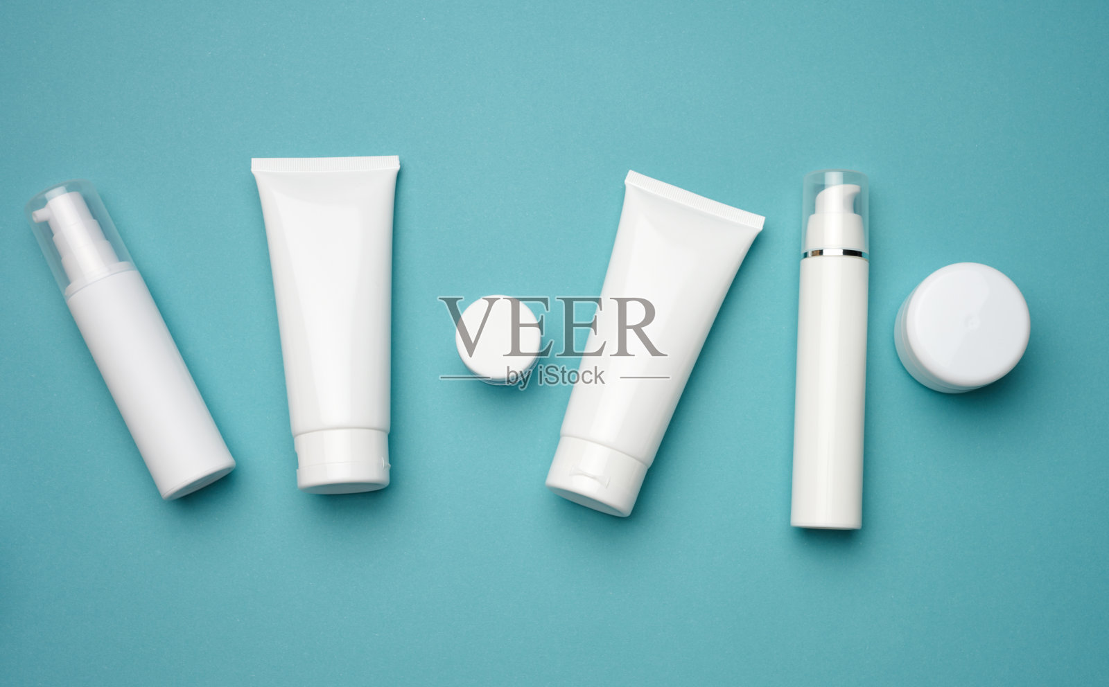 蓝色背景上的罐子、瓶子和用来装化妆品的白色塑料管。包装霜，凝胶，血清，广告和产品推广，模拟照片摄影图片