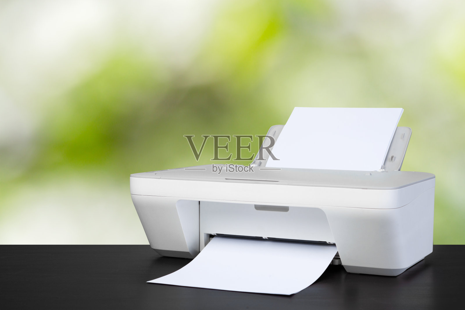 紧凑型激光打印机在黑色书桌上模糊的背景照片摄影图片