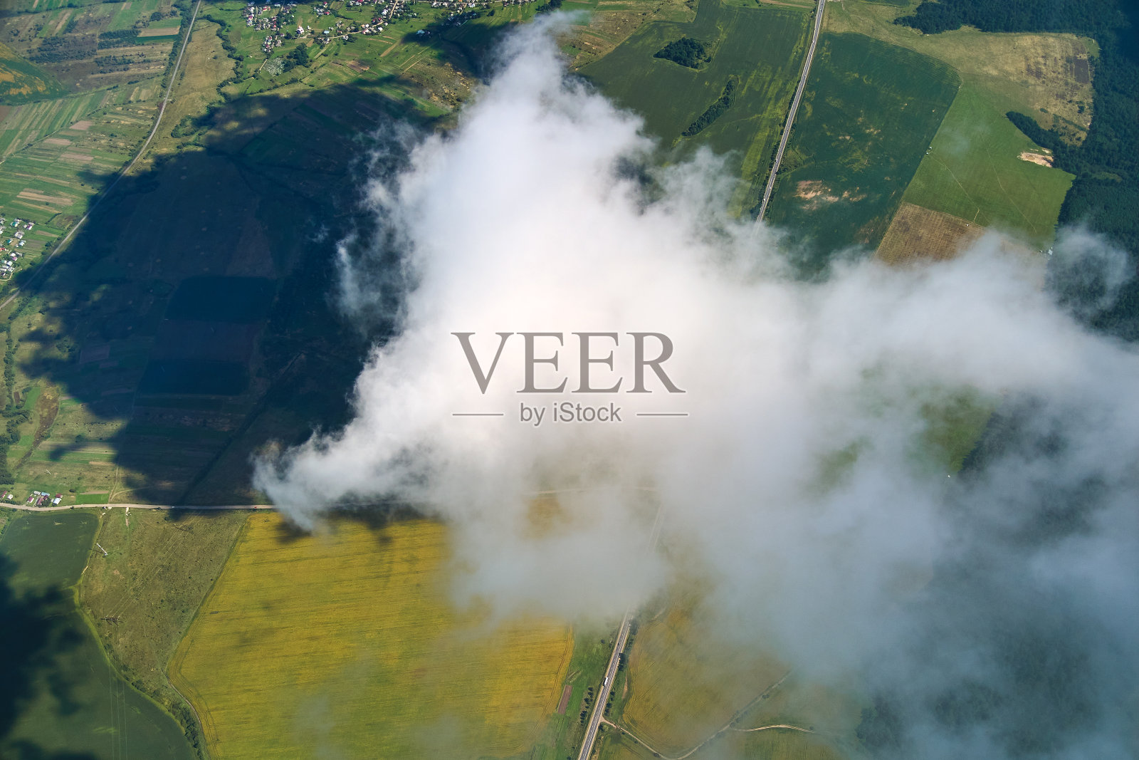 高空从飞机窗口鸟瞰被白色蓬松积云覆盖的地球。照片摄影图片