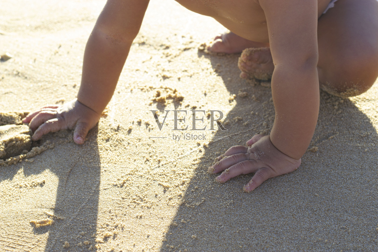 特写婴儿宝宝在海边玩湿沙摸沙，横卧画面照片摄影图片