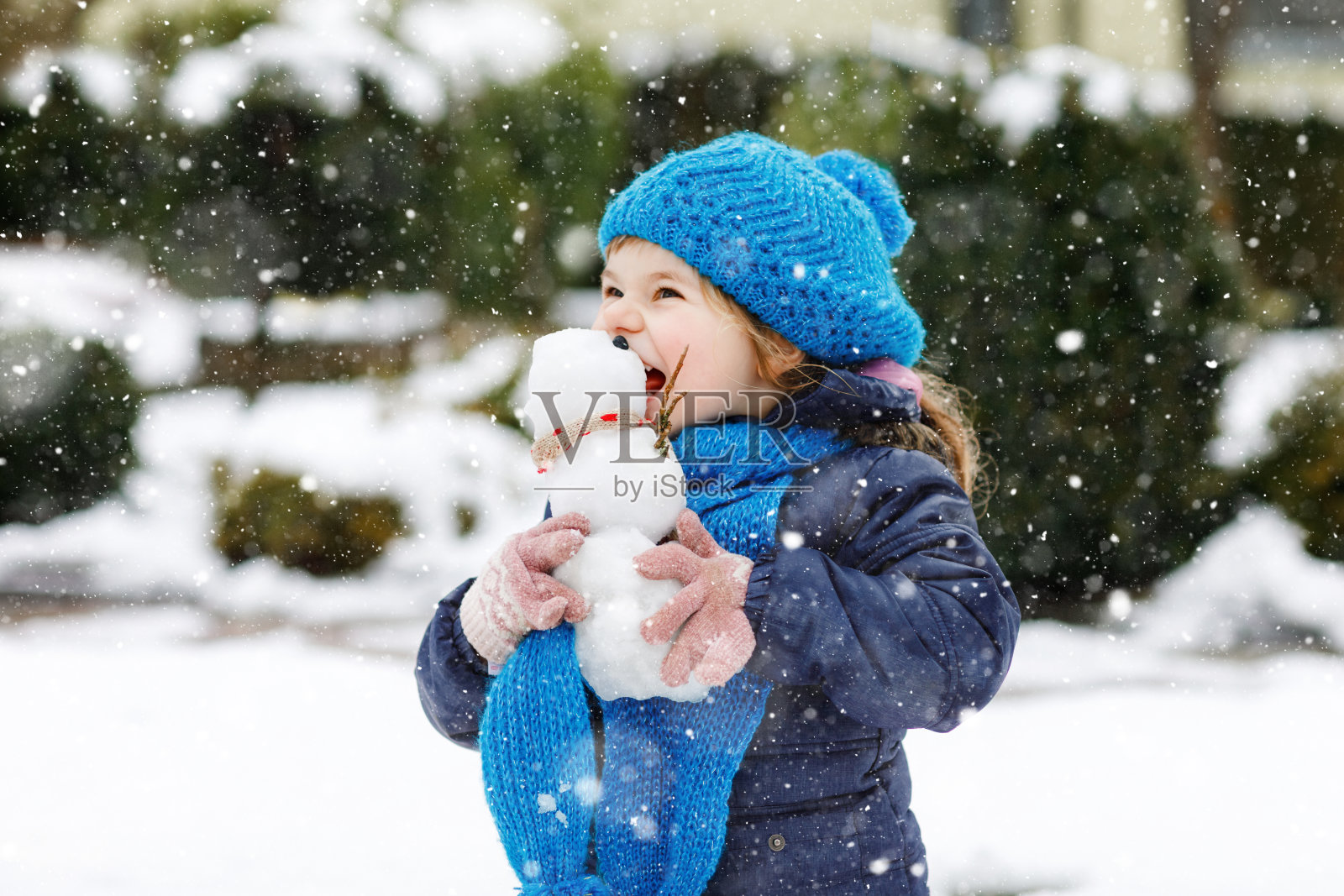 可爱的小女孩正在做迷你雪人，吃胡萝卜鼻子。可爱健康快乐的孩子在雪地里玩耍，在寒冷的日子里在户外玩耍。与孩子们在冬季积极休闲照片摄影图片