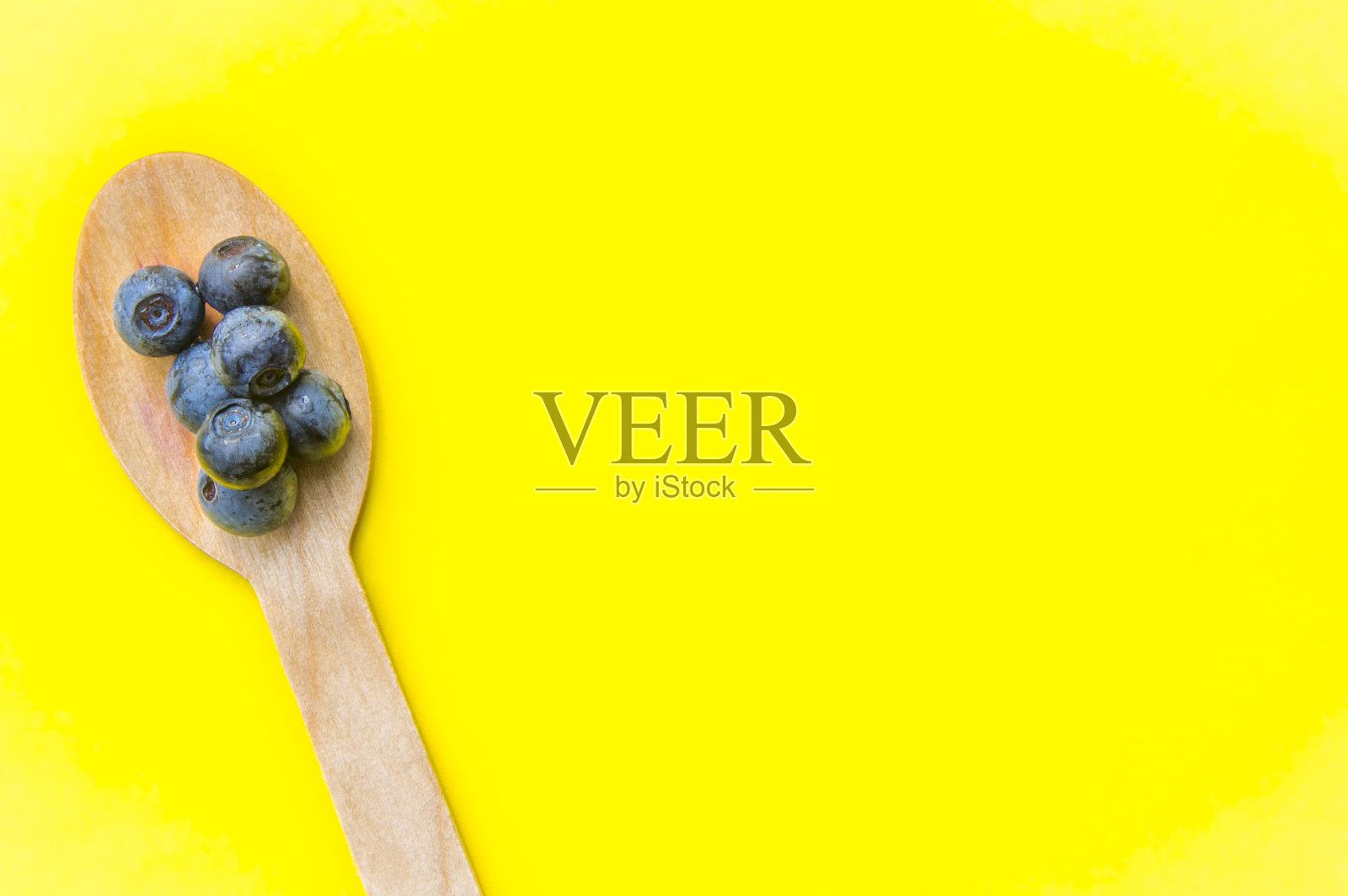 回收的勺子和多汁的新鲜蓝莓放在黄色的桌子上照片摄影图片