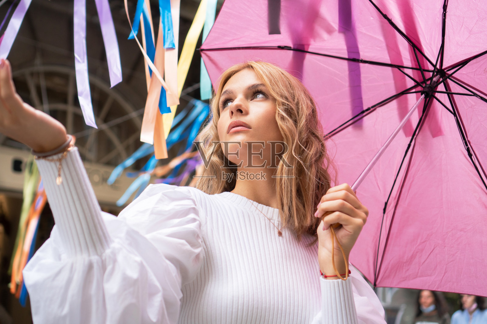 拿着粉红色雨伞的漂亮年轻女子照片摄影图片