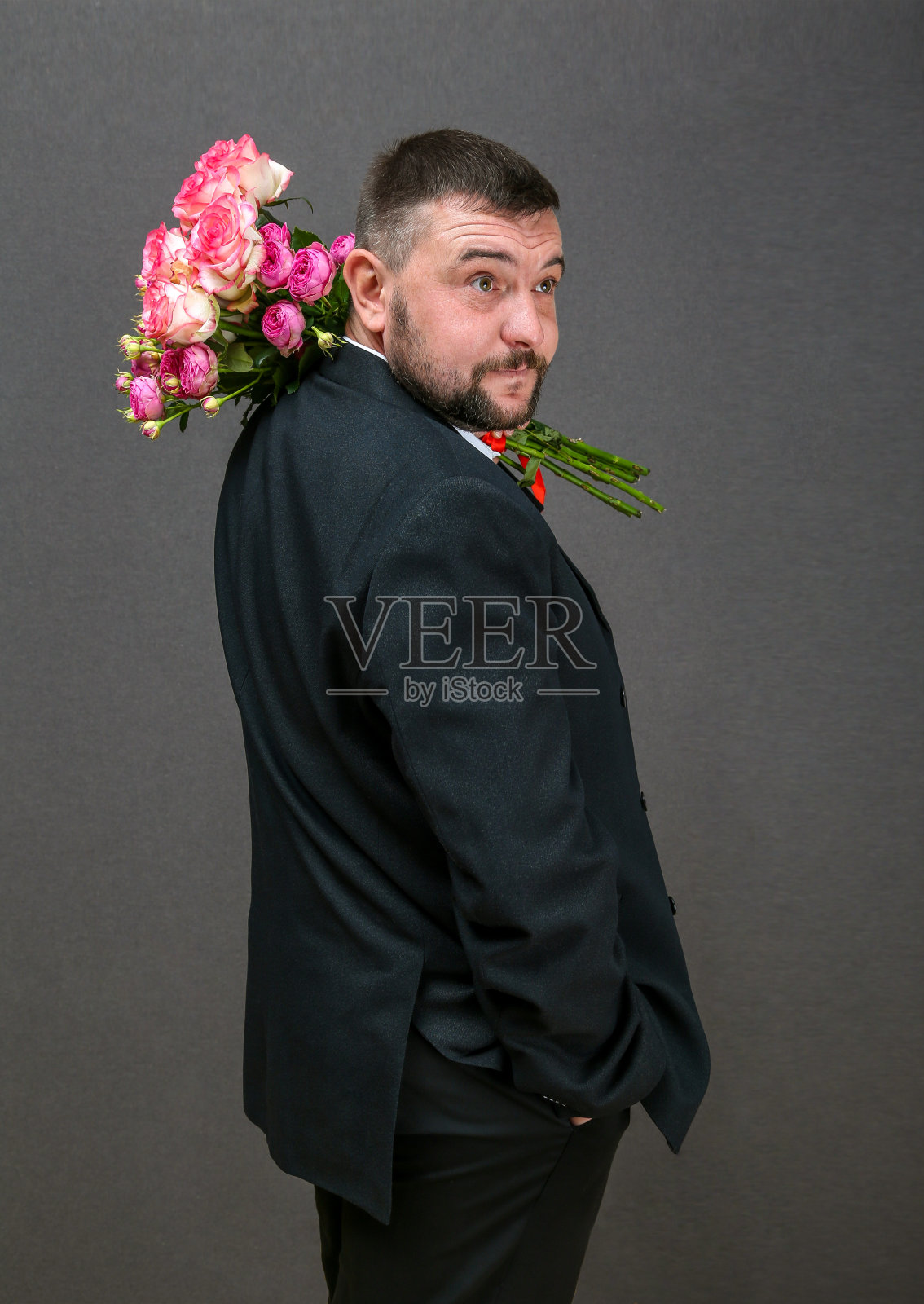 一个穿着夹克的年轻人的画像，手里拿着一束玫瑰花照片摄影图片