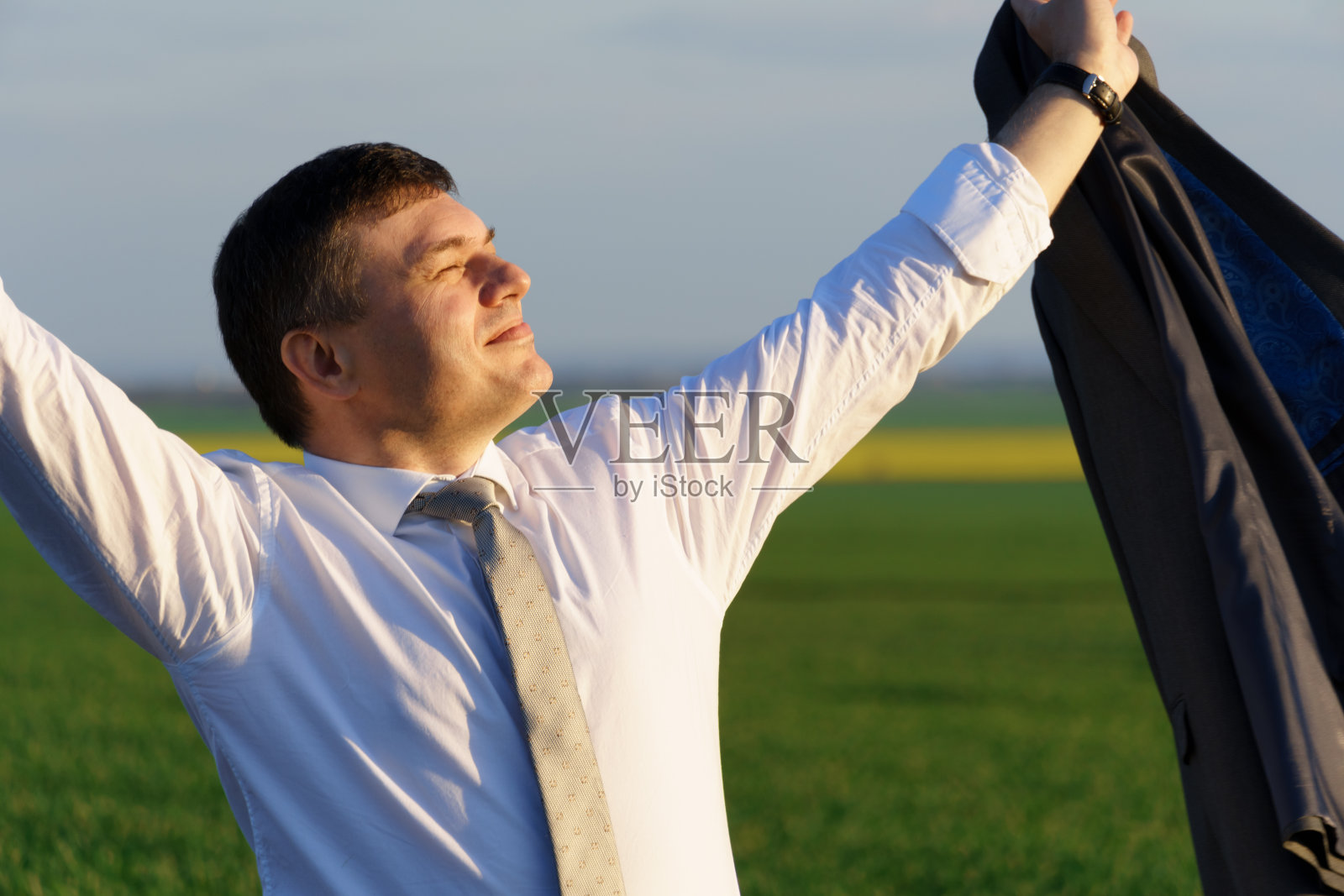 商人走在乡间小路上，绿色的田野，自由与商业的概念，绿草与蓝天为背景照片摄影图片