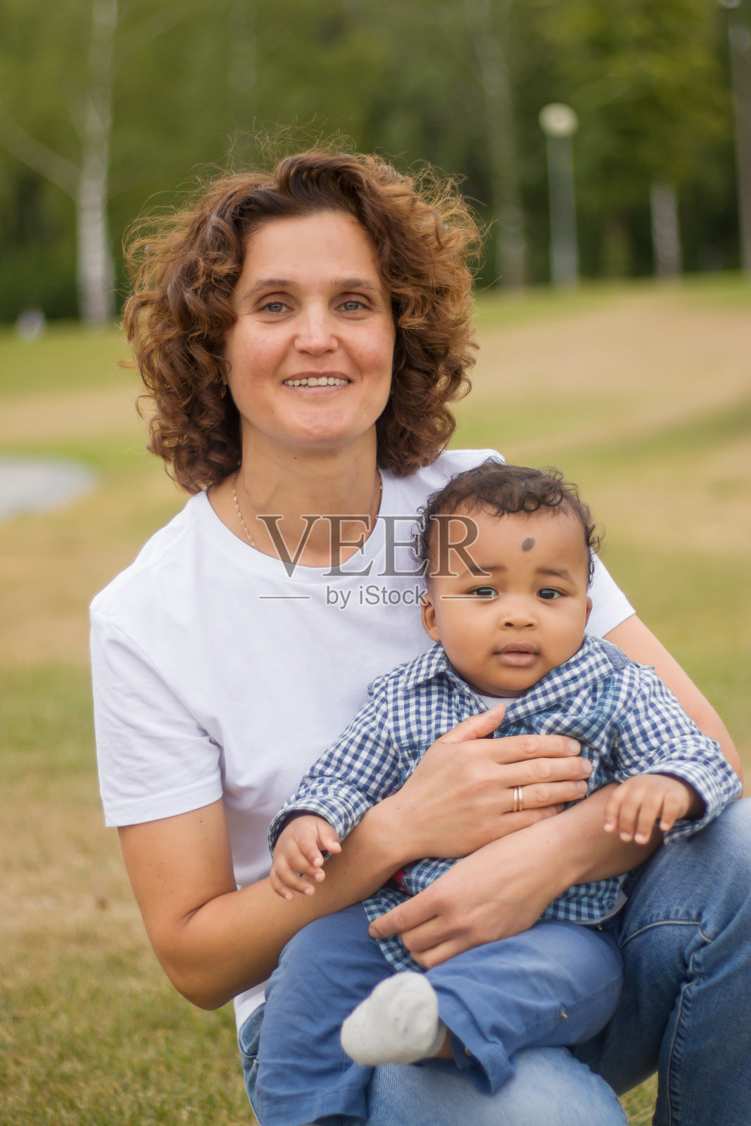 一个白皮肤的女人怀里抱着一个黑皮肤的婴儿照片摄影图片