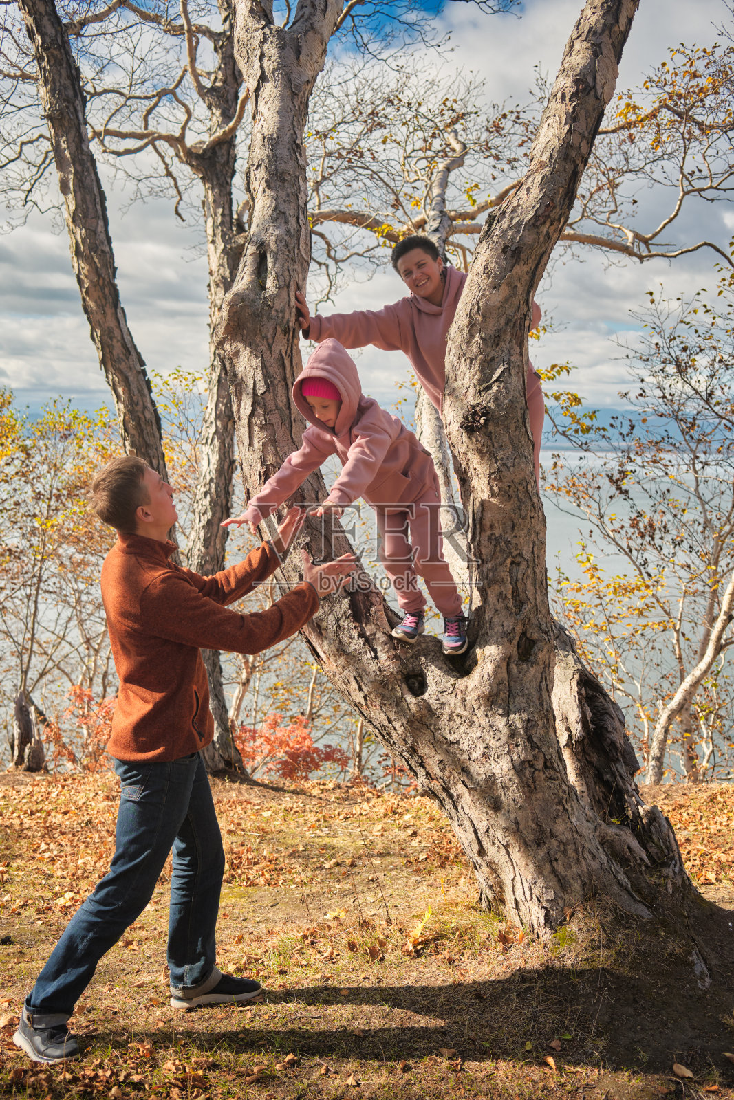 爸爸抱着从树上跳下来的女儿，把她抓住了照片摄影图片