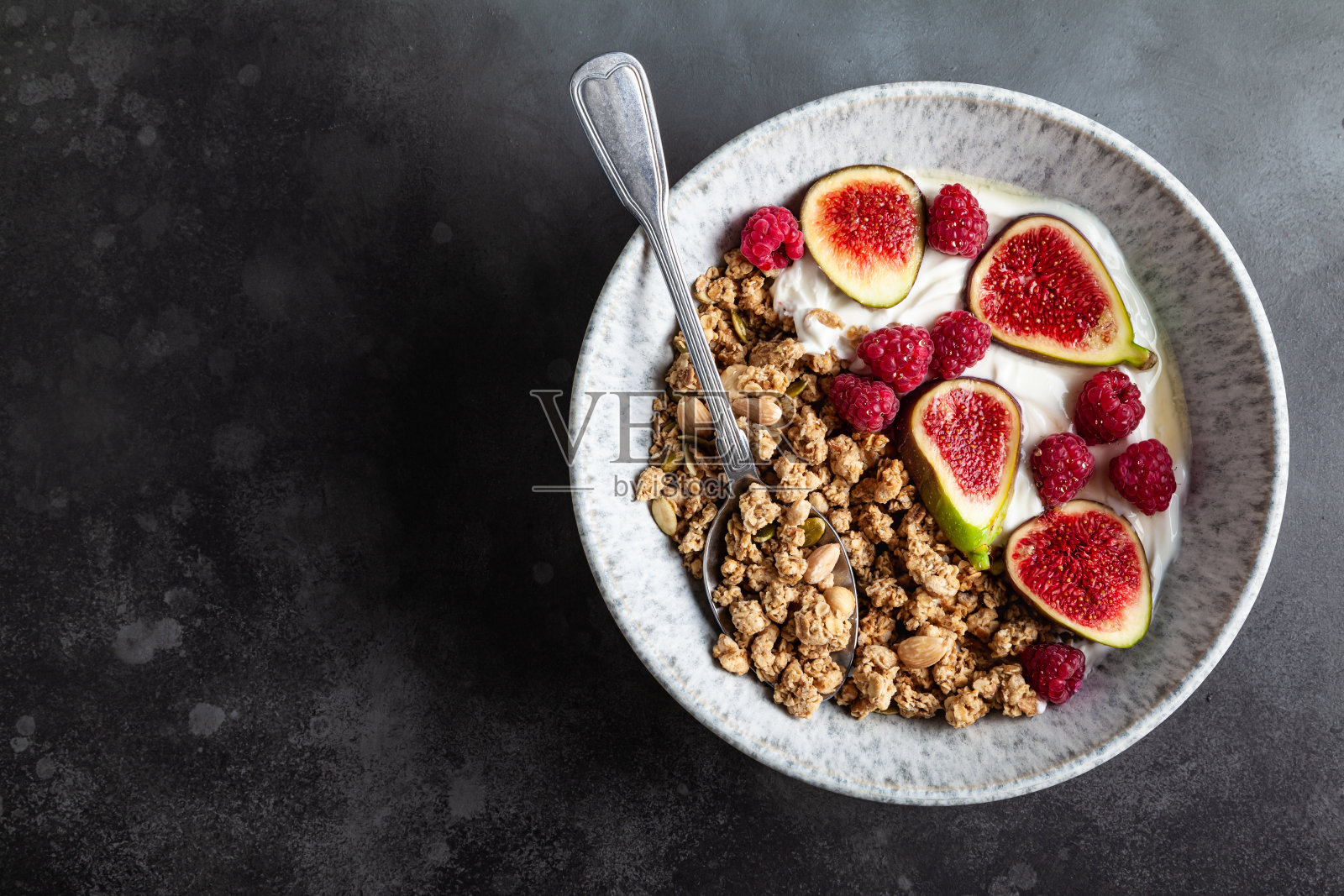 希腊酸奶加格兰诺拉麦片、无花果、树莓和蜂蜜。照片摄影图片