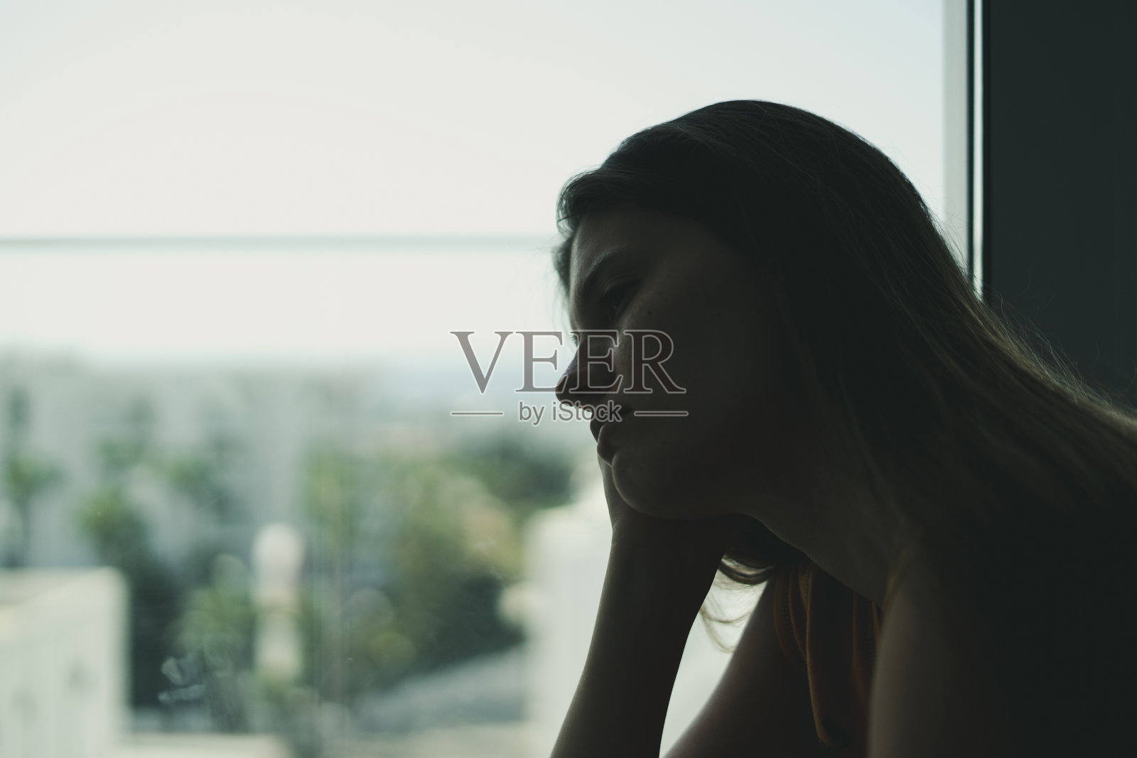 沮丧绝望地看着窗外的年轻女性照片摄影图片