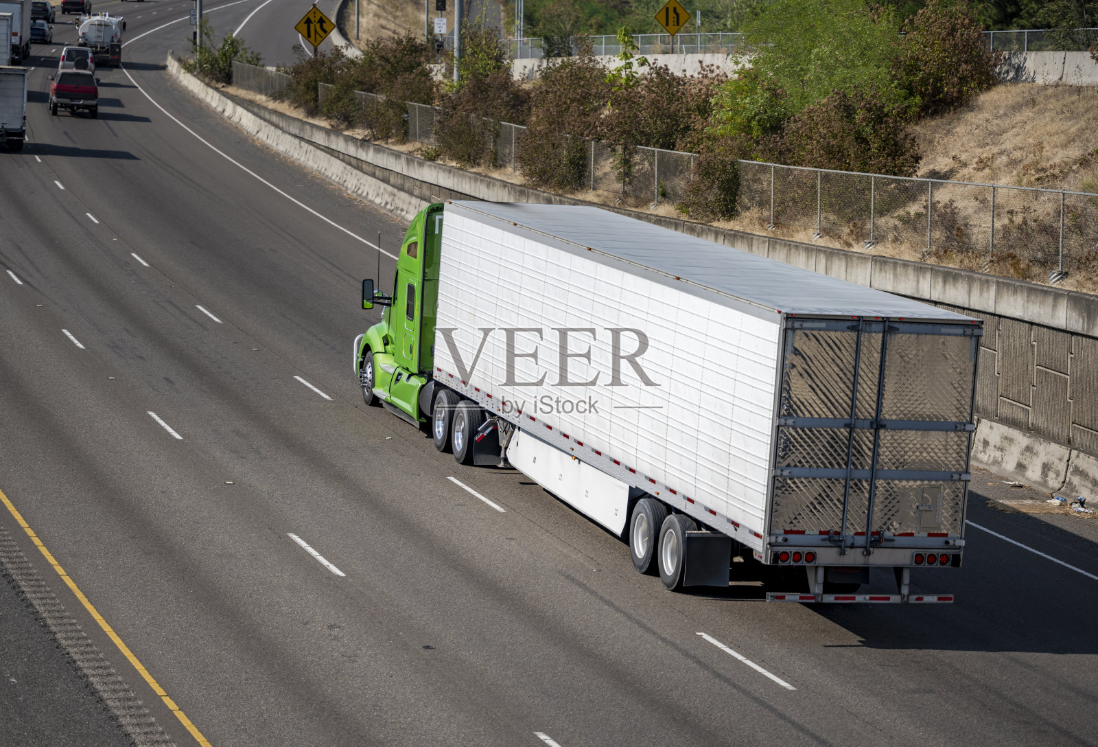 大功率大卡车绿色引擎盖半挂车，用冷藏半挂车运输冷冻货物，行驶在宽阔的多线公路上照片摄影图片