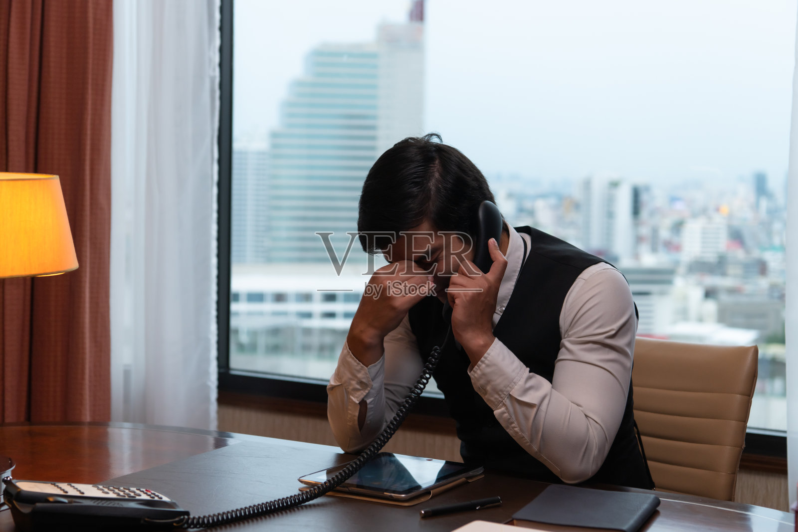 一个年轻的商人在他以城市为背景的办公室里监视和跟踪任务照片摄影图片