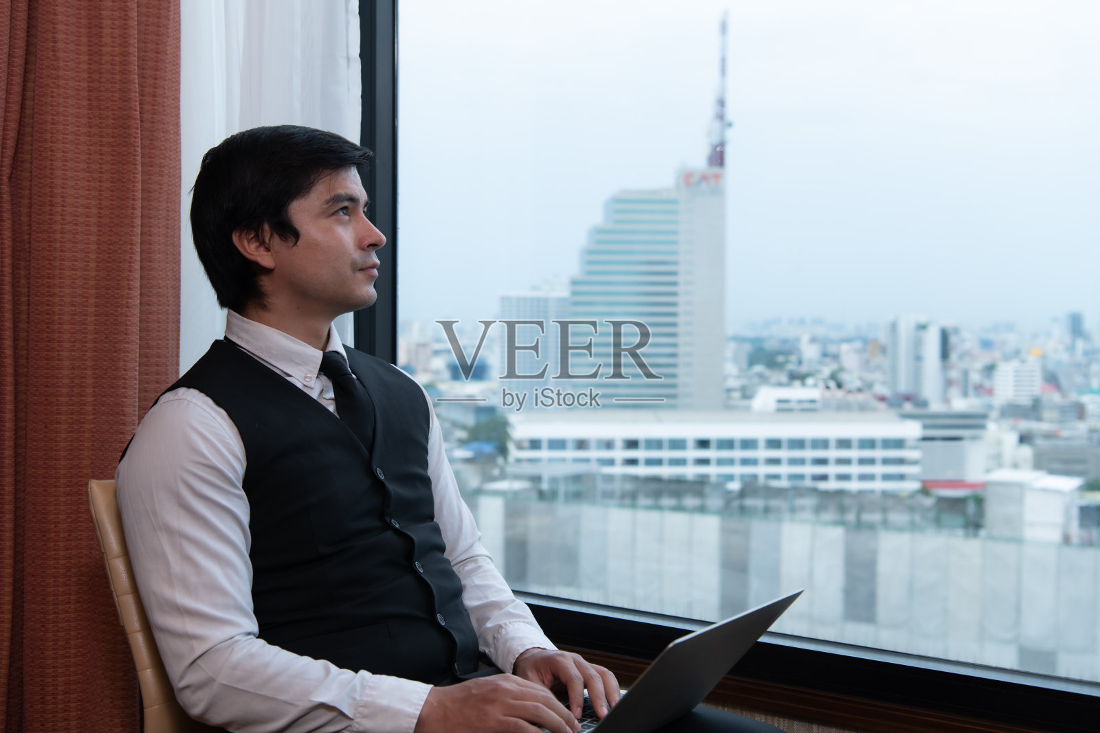 一个年轻的商人在他以城市为背景的办公室里监视和跟踪任务照片摄影图片