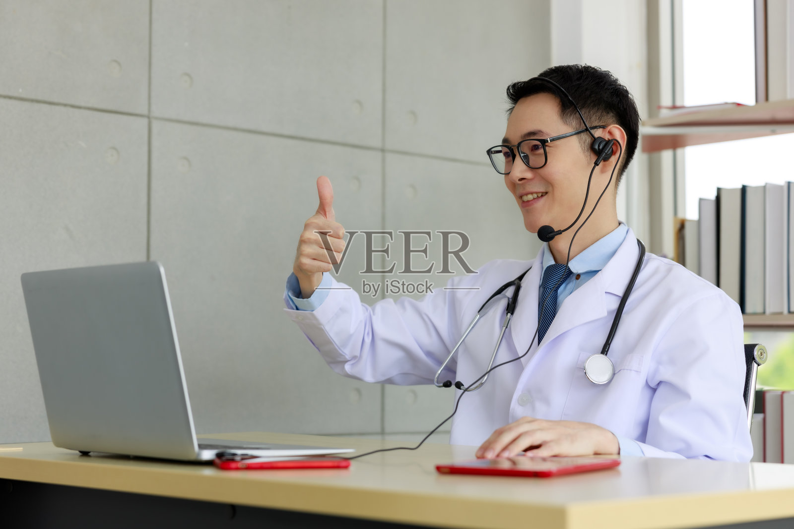 亚洲男子医生视频会议病人笔记本电脑，社会距离冠状病毒COVID-19概念照片摄影图片