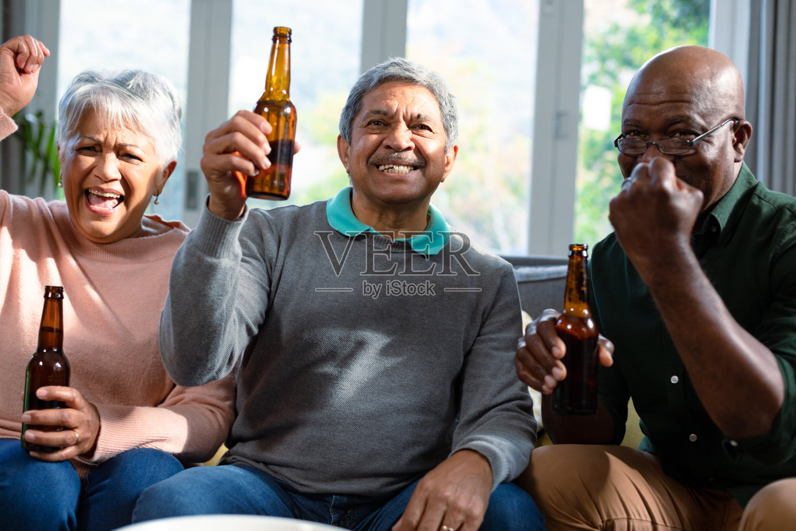 两对不同肤色的老夫妇和他们的非洲裔美国朋友在看电视和喝啤酒照片摄影图片