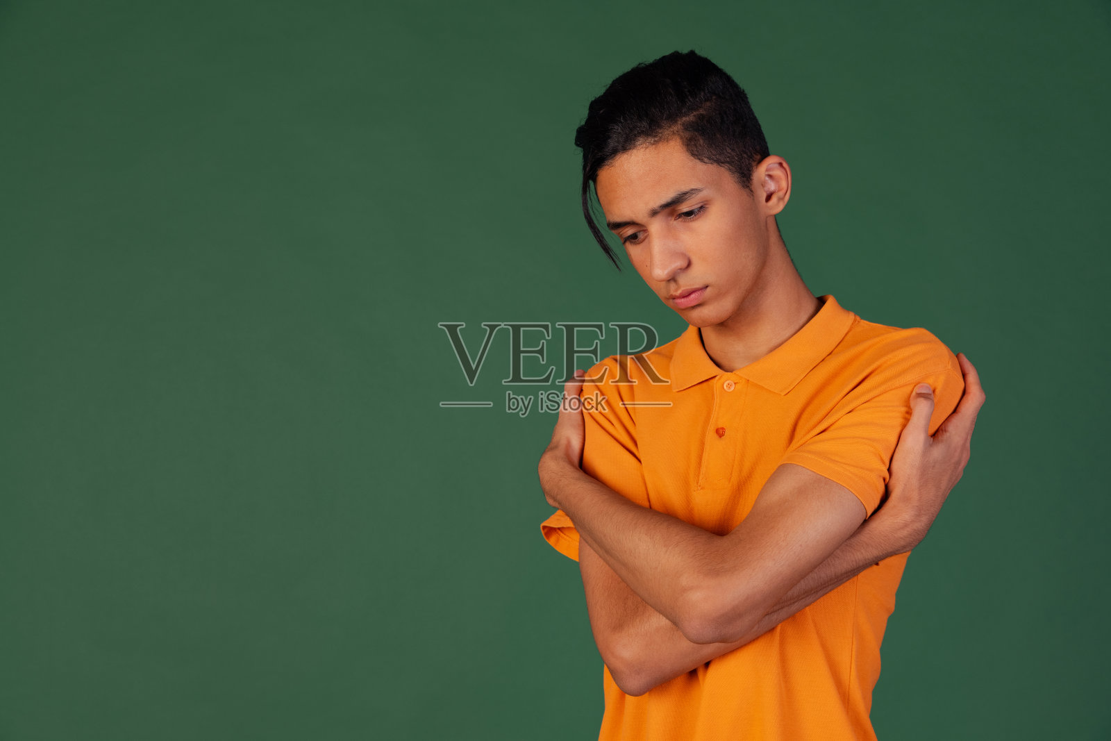 半身像的年轻英俊男子，学生在休闲服装孤立在绿色复古工作室的背景。人类情感的概念。照片摄影图片