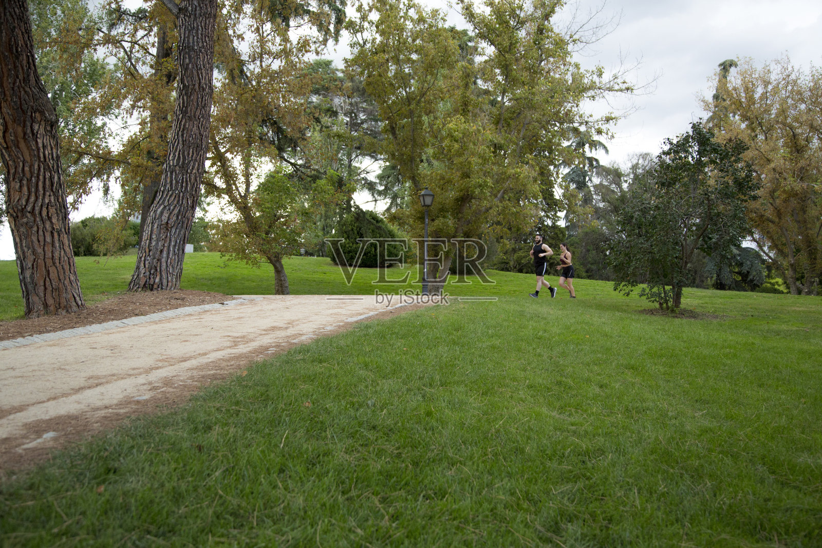 一对年轻的白人男女在公园的沙地上跑步照片摄影图片