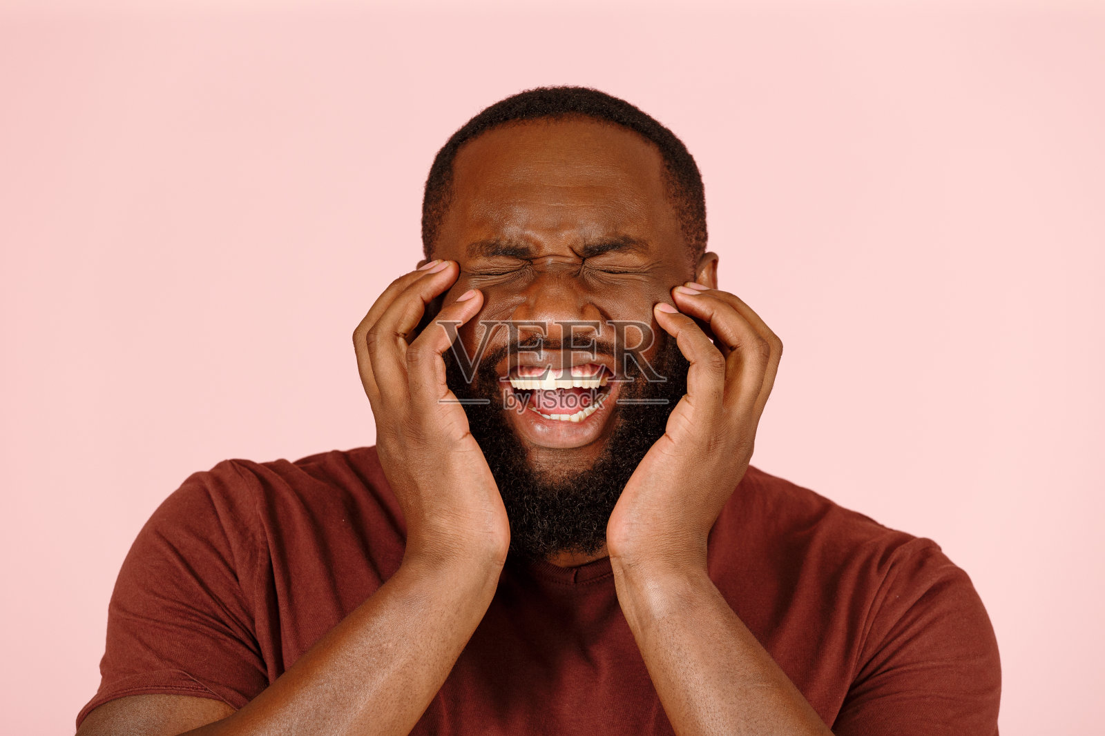 着迷的非裔美国男演员微笑着用手捧着粉红色的脸照片摄影图片