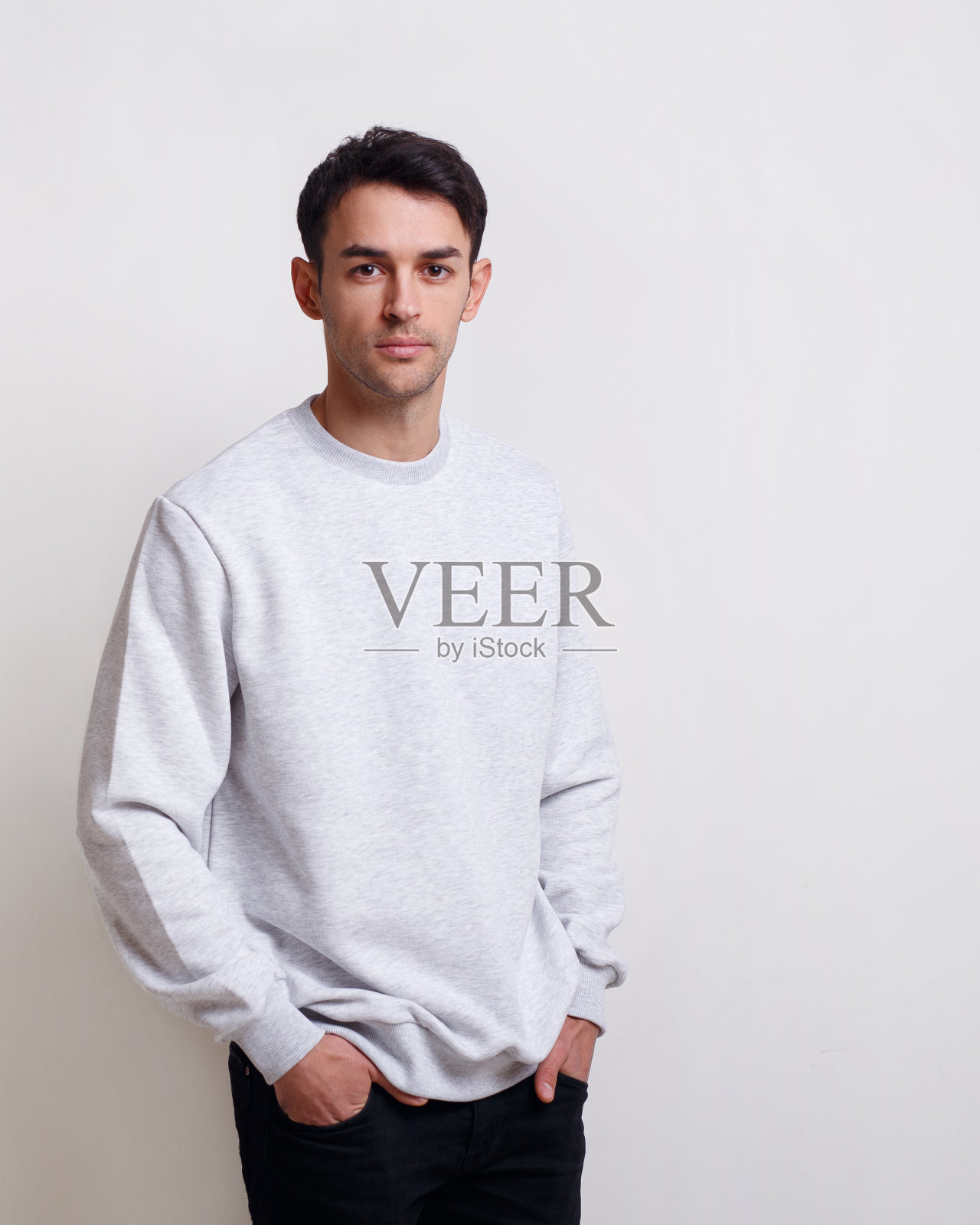 有魅力的年轻男子，灰色套头衫和牛仔裤，孤立的白色背景。照片摄影图片