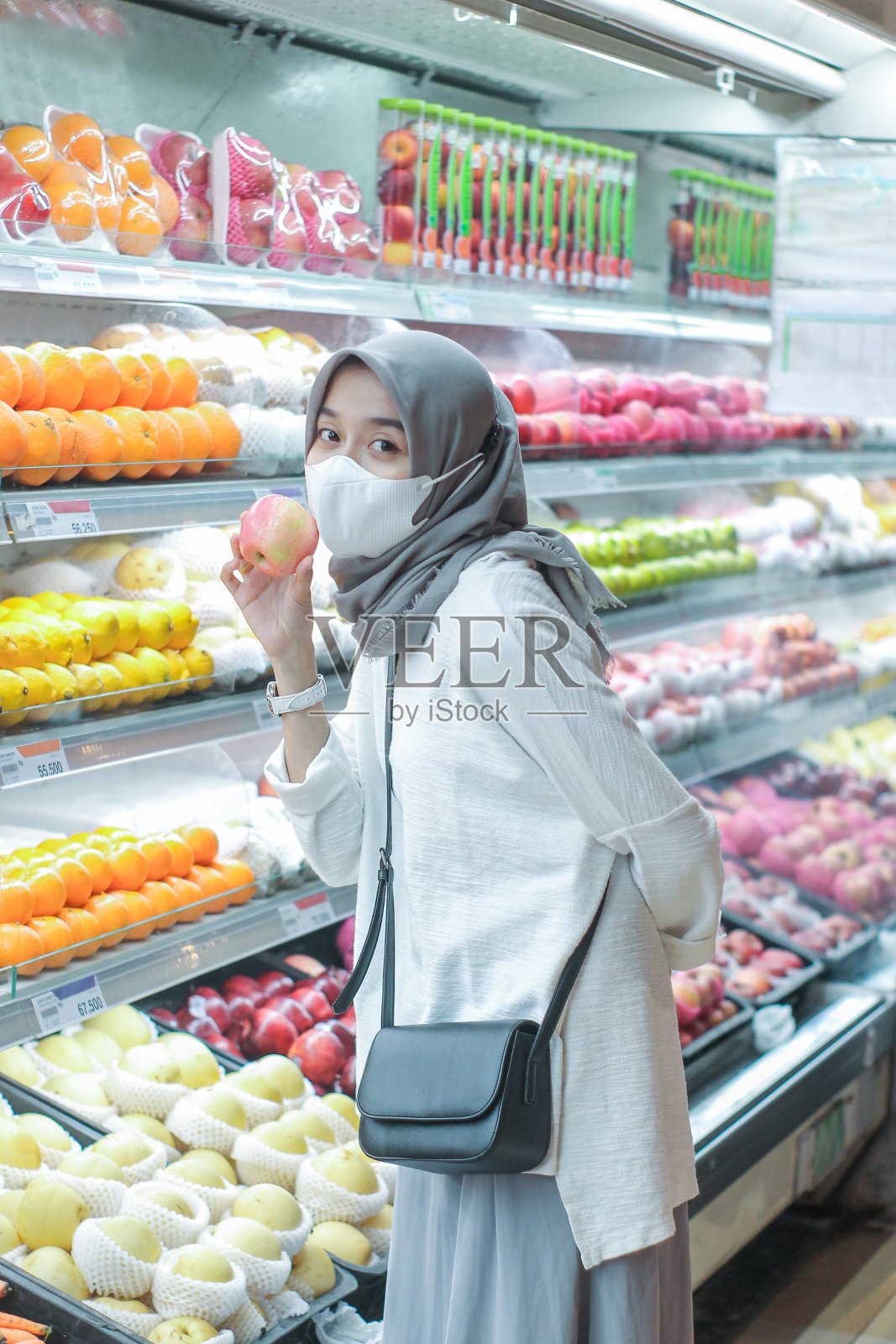 亚洲年轻女子戴着口罩在超市买水果照片摄影图片