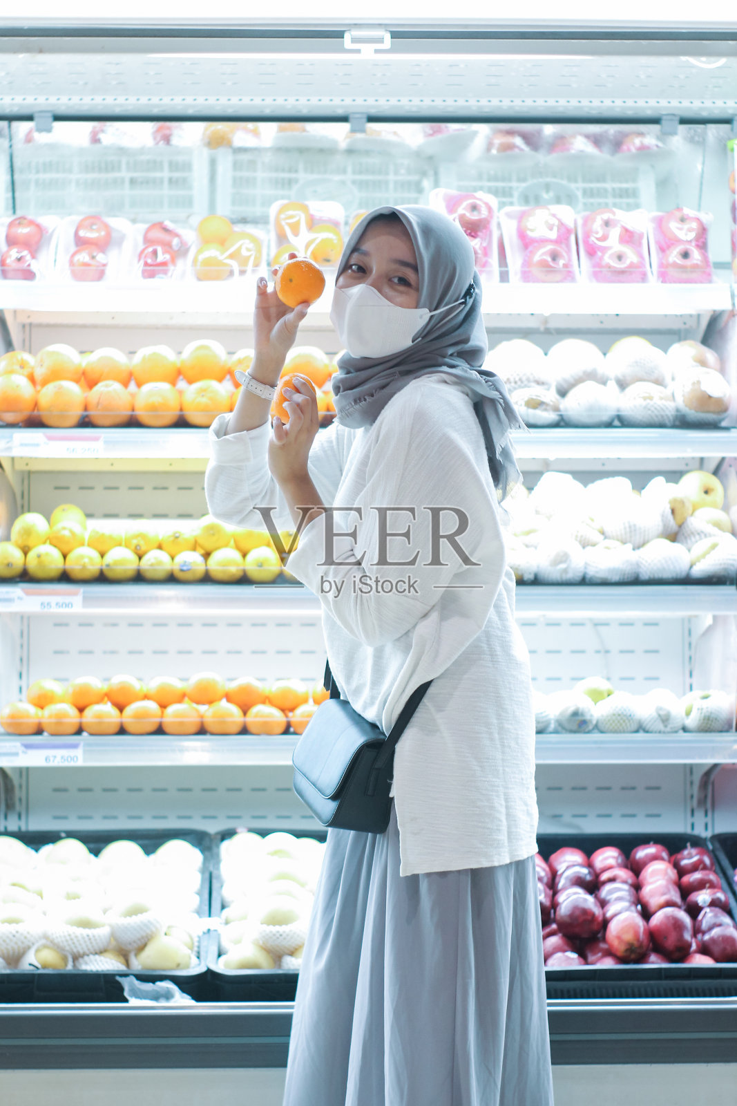 亚洲年轻女子戴着口罩在超市买水果照片摄影图片