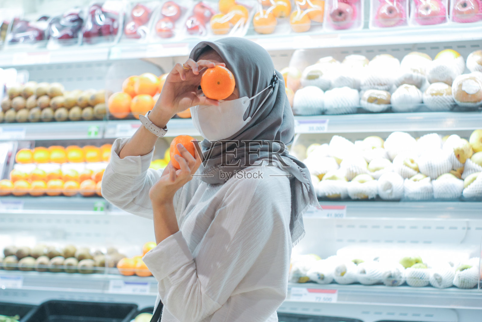 亚洲年轻女子开朗有趣，戴着口罩在超市购物水果照片摄影图片