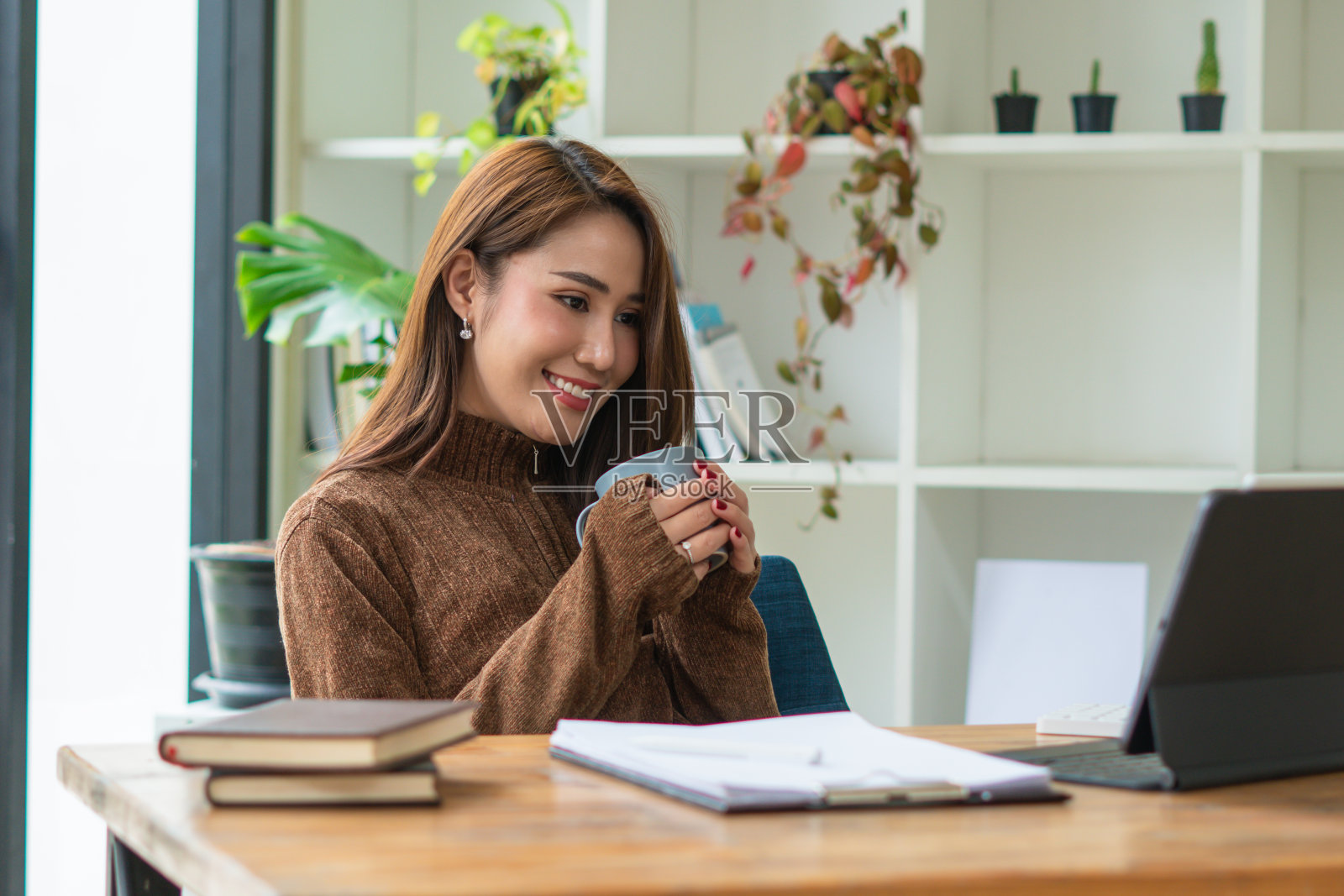 美丽可爱的亚洲年轻女商人在咖啡馆，使用数码平板电脑和喝咖啡微笑照片摄影图片
