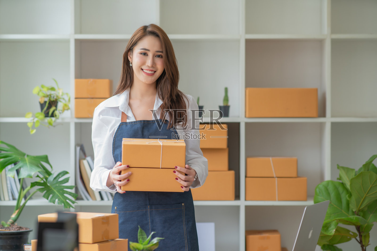 照片中年轻美丽的企业家拿着包裹盒站在她的商店，微笑着看着相机，在线商务快递照片摄影图片