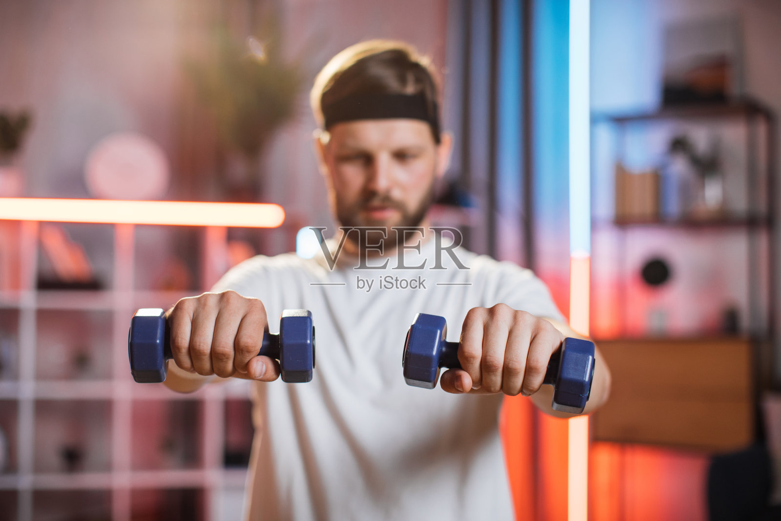 头带微笑的男人在家里用哑铃锻炼照片摄影图片